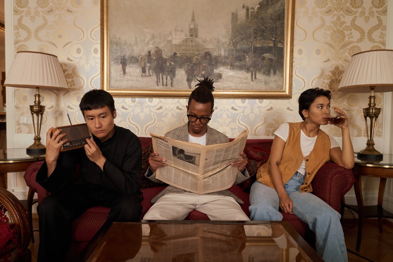 Three adults reading and relaxing on a couch in a stylish living room with classic decor.